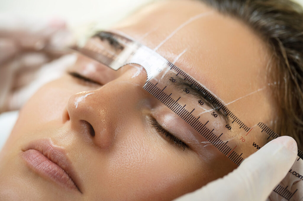 Woman during professional eyebrow mapping procedure